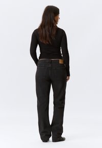 Jeans in denim nero con una vestibilità ampia, vita media e un patch in pelle tan sul retro. Presentano due tasche posteriori e cuciture minimali.