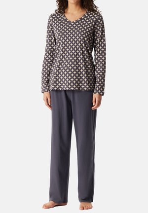 Långärmad pyjamaströja i beige med ett mörkt geometriskt mönster; parat med löst sittande pyjamasbyxor i mörkgrått. Mjuk tygstruktur.
