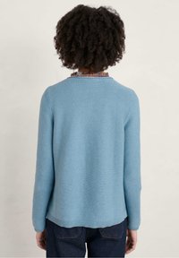 Lichtblauwe geribbelde trui met lange mouwen, ronde halslijn en een losse pasvorm. De achterkant heeft een gestructureerd oppervlak, afgewerkte randen en geen zichtbare versieringen.