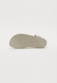 Shoe sole features a flexible, light gray rubber material with a textured pattern of interwoven curves for enhanced grip.