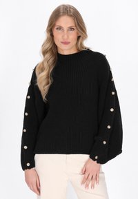 Maglione nero a maglia con texture a coste, colletto rotondo e maniche a palloncino, caratterizzato da bottoni dorati decorativi lungo i lati.