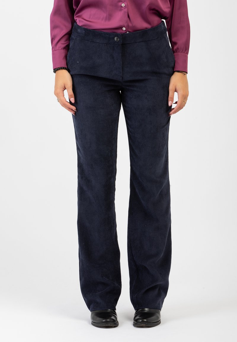 Pantaloni di velluto a coste blu navy con design a gamba dritta, dotati di una vita piatta e chiusura con un unico bottone. Tessuto testurizzato a coste larghe.