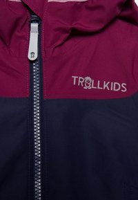Maroon and navy waterproof jacket featuring a front zipper, hood, and "TROLLKIDS" logo with a graphic accent. Smooth fabric texture.