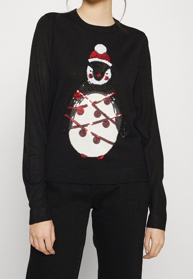 Maglione lavorato a maglia nera con un design di pinguino decorato con paillettes rosse e bianche, adornato con luci a stringa rosse e un berretto con pompon rosso e bianco.