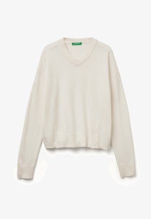 Pull court couleur crème avec décolleté en V, poignets côtelés et une texture complexe. Présente des coutures diagonales sur le devant.