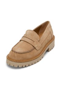 Mocassin en suède beige avec un capuchon de pied cousu, un détail de sangle ajustable et une semelle en caoutchouc épaisse avec des rainures texturées.