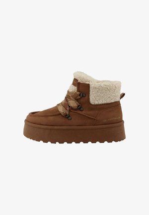Brown suede ankle boots with a fluffy cream collar, featuring brown laces, metal eyelets, and a thick, textured sole. Brand logo displayed.