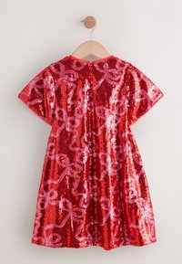 Abito in paillettes rosse con maniche corte, caratterizzato da un motivo a fiocco rosa. Progettato con scollo rotondo e una texture vibrante e lucente.