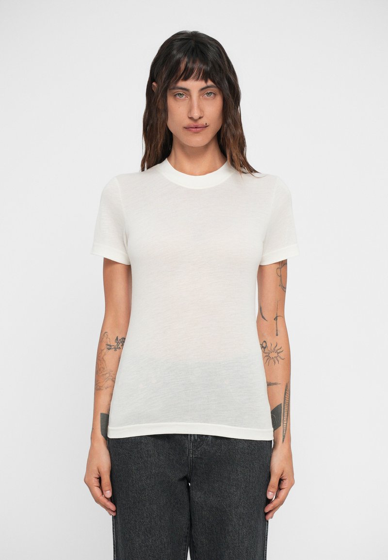Tricou alb cu mânecă scurtă, fabricat dintr-un material ușor și semi-transparent, având un guler cu dungi și o siluetă ajustată.