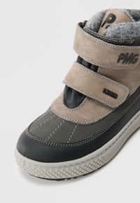 Bottes synthétiques marron et grises avec des bandes Velcro, des semelles en caoutchouc et des accents cousus. Détails texturés sur les orteils et doublure en fourrure visible.