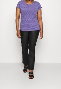 Haut court violet à manches courtes avec un motif géométrique, associé à un pantalon flare noir et des sandales à lanières noires. Design simple, tissu doux.