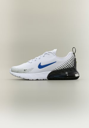 Biały sneaker Nike Air Max z niebieskim logo, czarnym kropkowanym wzorem w pobliżu pięty oraz widoczną amortyzacją w czarnej podeszwie, widok z boku na neutralnym tle.