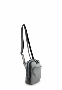 Sac d'épaule en tissu gris avec deux compartiments zippés, une poche avant et une sangle ajustable fine. Texture lisse avec des détails accentués foncés.