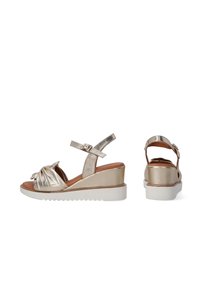 Goldene metallische Wedge-Sandalen mit einer geknoteten Vorderseite, verstellbarem Knöchelriemen, gepolsterter Innensohle und einer weißen Gummisohle mit Zickzackstruktur.