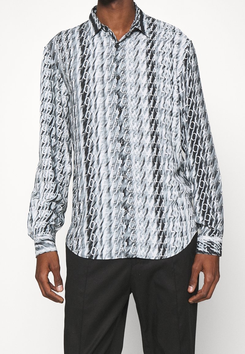 Camicia a maniche lunghe con bottoni, caratterizzata da un motivo astratto bianco e nero con design di testo ripetuto e colletto standard. Tessuto morbido al tatto.