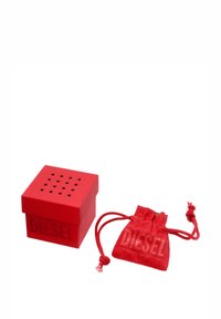 Red silicone square box with perforated lid, labeled "DIESEL," accompanied by a matching drawstring pouch. Textured surface.