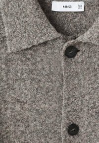 Abrigo de mezcla de lana gris con cuello con solapa, superficie texturizada y botones negros. Presenta etiqueta con la marca "MNG" cerca del cuello.