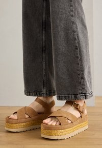 Sandalias de plataforma de ante marrón con tiras entrecruzadas, que cuentan con una suela media envuelta en yute y una suela de goma resistente.