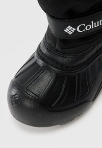 Sorte vanntette vinterstøvler med teksturert gummitå og stropp med Columbia-logo på hvit bakgrunn.