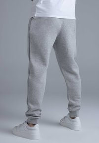 Grey sweatpants with cuffed hems, made of soft material, shown worn with white sneakers. Simple design, no visible patterns or details.