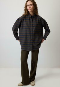 Majica z dolgimi rokavi in ovratnikom v mornarsko modri barvi s horizontalnimi črtami v olivni in bordo barvi, z gumbi spredaj in sproščenim krojem.