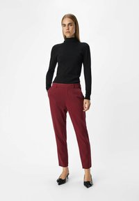Pull à col roulé noir simulé, pantalon sur mesure couleur bordeaux avec poches, et talons noirs à bout pointu. Design élégant, ajusté avec tissu lisse.