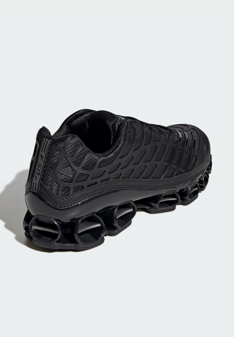 Chaussure de sport noire avec une tige texturée, des contours profilés et un design unique de semelle segmentée. Présente un logo sur le talon.