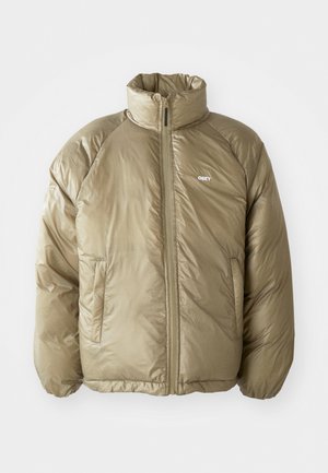 Chaqueta acolchada de color marrón claro con alto cuello, cremallera frontal, bolsillos laterales y pequeño logo blanco "OBEY" en el pecho izquierdo.