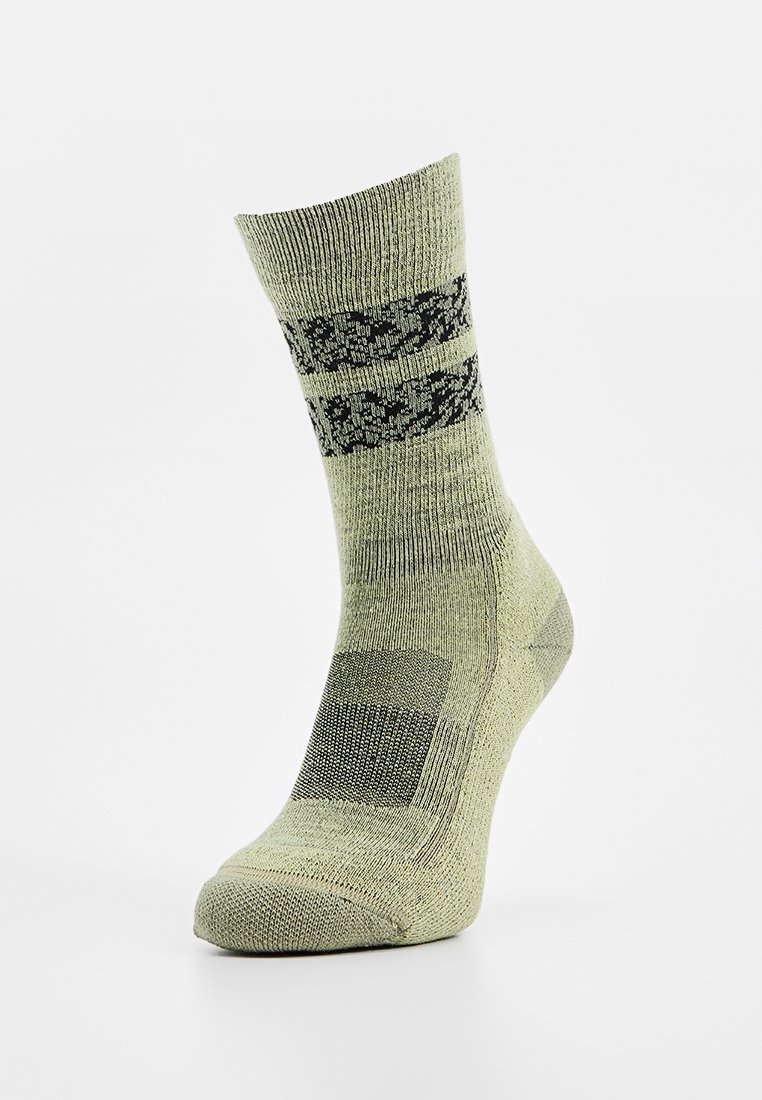 Chaussette tricotée verte avec un motif de blocs texturé et des accents noirs. Hauteur cheville avec un talon et un orteil renforcés pour le soutien.
