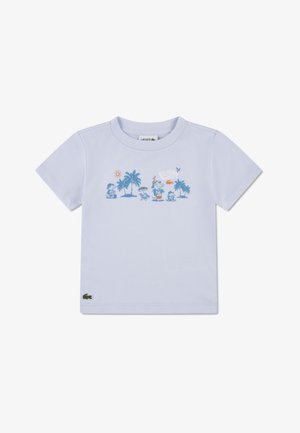 Világoskék, rövid ujjú pamut póló. Az elején pálmafák, nap és játékos karakterek grafikája látható. A Lacoste logó a szegélyen.