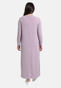 Langes, figurbetontes Kleid in hell-lila Farbe, aus glattem Stoff gefertigt. Es hat lange Ärmel, einen geraden Schnitt und eine Rückennaht als Detail.