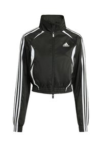 Giacca nera cropped realizzata in materiale leggero, presenta un colletto alto, una cerniera completa, strisce bianche sui lati e un logo ricamato sul petto.