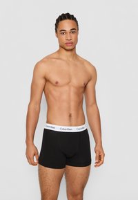 Čierne bavlnené boxerky s bielym logom Calvin Klein na páse. Materiál je hladký s priliehavým strihom a krátkymi nohavičkami.
