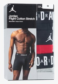 Boxeri negri cu talie albă inscripționată cu "JORDAN"; include opțiuni în roșu și gri. Ambalajul prezintă un model care poartă boxeri negri.