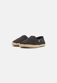 Baskets slip-on en toile noire avec une semelle en jute espadrille texturée, dotées d'un bout arrondi et de coutures discrètes.