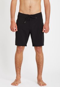 Shorts de bain noirs en tissu léger. Ils disposent d'une taille avec cordon de serrage et de poches latérales. Design classique, arrivant au genou.