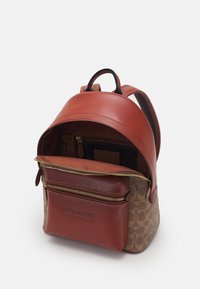 Brązowy plecak skórzany z teksturowanym brązowym wzorem, zapinaną na zamek przednią kieszenią i wewnętrznymi przegródkami. W zestawie regulowane szelki.