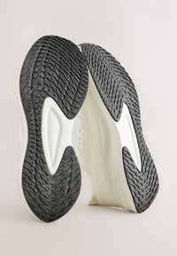 Chaussures de sport légères avec une semelle extérieure en caoutchouc noir texturé, une semelle intermédiaire blanche et une tige en mesh respirant à finition lisse.