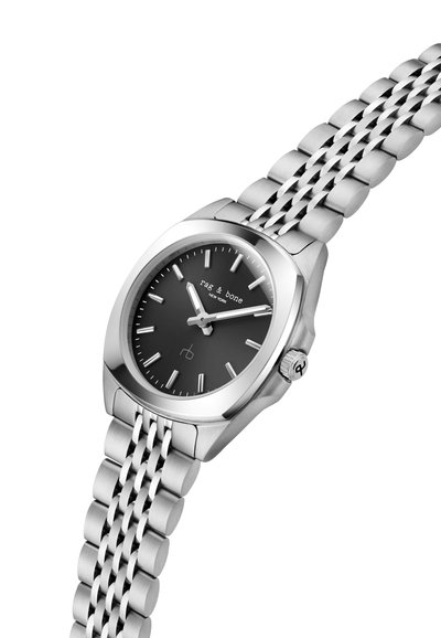 Zegarek ze stali nierdzewnej z czarną tarczą, srebrnymi znacznikami i wskazówkami. Posiada bransoletę meshową oraz koronkę z boku.