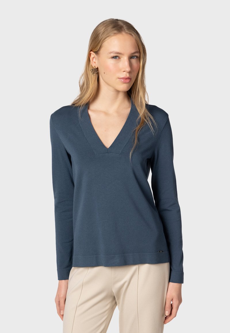 Tummansininen pitkähihaisuus pusero V-pääntiellä, valmistettu pehmeästä kankaasta. Ominaisuuksiin kuuluu rento istuvuus ja hillitty logo yksityiskohtana helmassa.