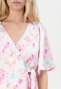 Λουλουδάτο φόρεμα τύπου wrap σε παστέλ χρώματα με πολύ βαθύ V-ντεκολτέ, κοντά φουσκωτά μανίκια και ζώνη στη μ�έση. Μαλακό ύφασμα με σχέδιο υδατογραφίας.