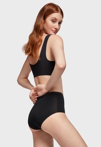 Ensemble de sous-vêtements noir sans couture, fabriqué dans un matériau doux et extensible, avec un design épuré et minimaliste ainsi qu'une bordure festonnée à la taille.