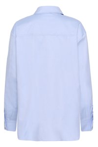 Camisa azul claro de manga larga con botón y cuello, con costuras visibles y puños abotonados, mostrada desde atrás sobre un fondo blanco.