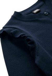 Navy blue cardigan made of soft fabric with a round neckline, featuring ruffled details on the shoulders and a button closure.