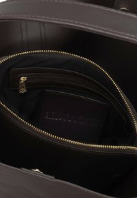 Interno di una borsa in pelle marrone, dotato di una tasca con cerniera e diversi scomparti, foderato in tessuto nero e con dettagli in metallo dorato.