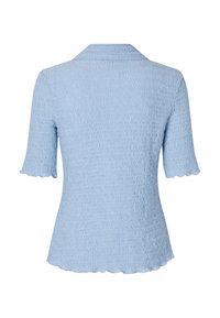 Top azul claro, de mangas curtas, com uma textura ondulada e bainha rendilhada. Apresenta um colarinho suave e uma silhueta ajustada.