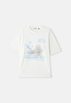 Camiseta blanca de gran tamaño con agujeros desgastados, gráfico azul de palmeras, formaciones rocosas, sol y texto que dice "Septiembre 1969 Ibiza".