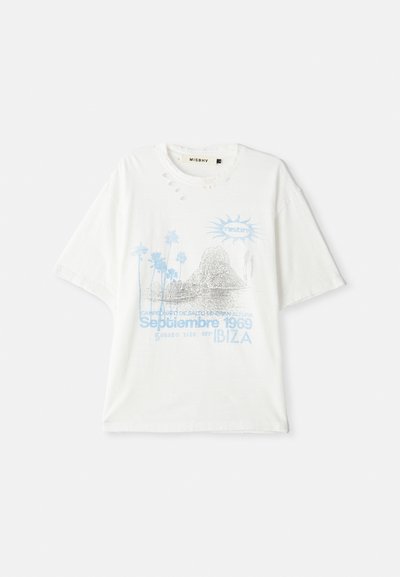 Camiseta blanca de gran tamaño con agujeros desgastados, gráfico azul de palmeras, formaciones rocosas, sol y texto que dice "Septiembre 1969 Ibiza".