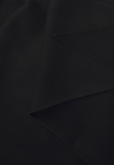 Black wool fabric, smooth texture, folded, with a slight sheen. Features sharp angular lines from layering and draping of material.