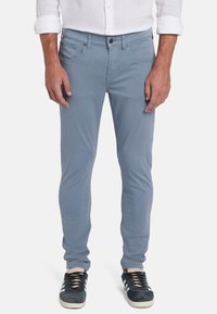 Lichtblauwe katoenen pantalons met een slim fit, voorkwestern en een knoopsluiting. Gecombineerd met donkere sneakers met witte accenten.